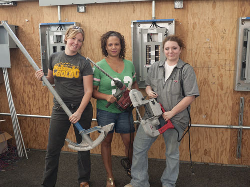 Women electrical apprentices posing with large tools